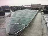 Tetto di vetro con costruzione portante in acciaio appoggiata sul tetto di un edificio residenziale concepito come copertura del cortile interno.